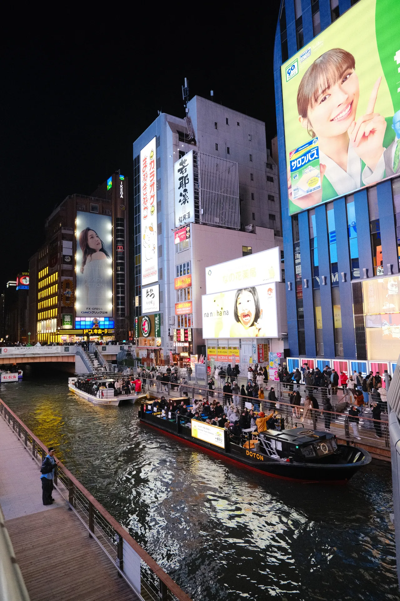 Canal de Dōtonbori à noite, com barcos e letreiros acesos, em Osaka
